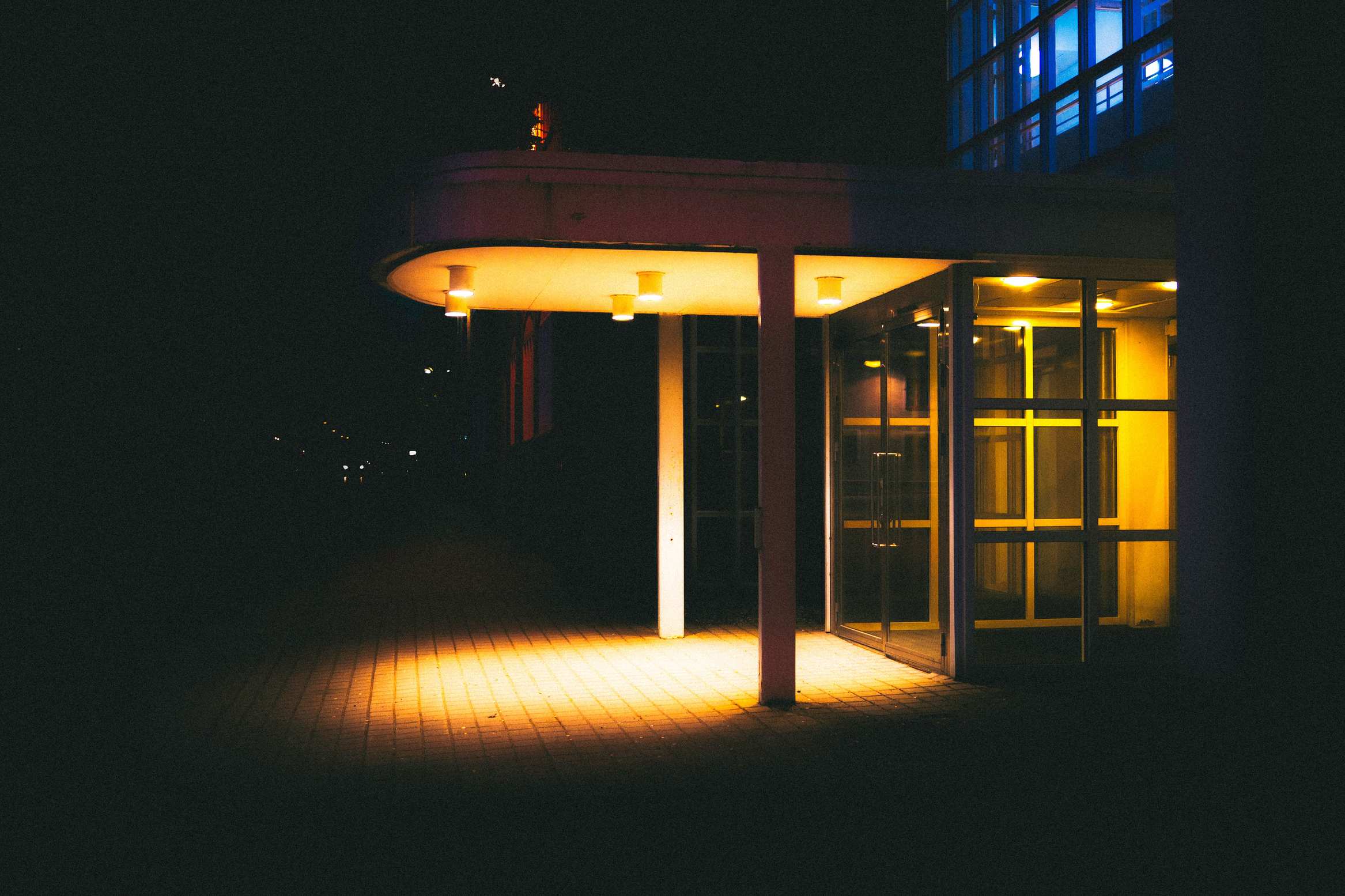Office building exterior at night with lit windows, modern building entrance with warm glowing lights